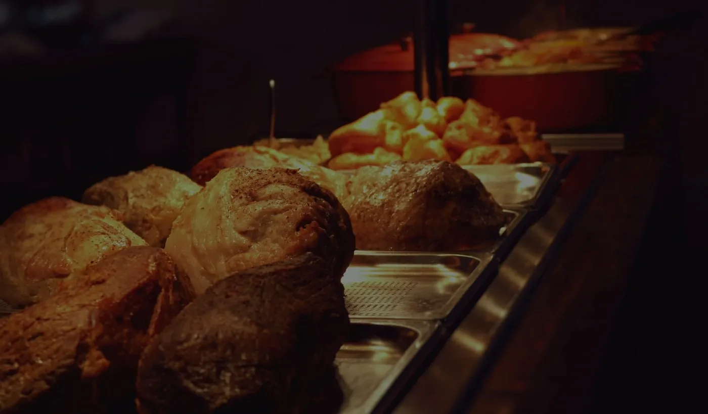 A carvery roast joint being sliced at Countrystyle Kitchen in Lancaster, with crackling and gravy visible on the cutting board